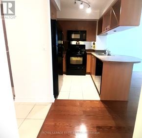 Mississauga (City Centre) condo for rent - A kitchen with a black refrigerator and wooden floors.