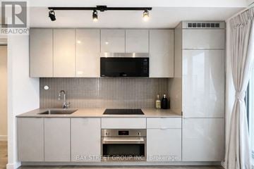 Toronto (Bay Street Corridor) condo for rent - A modern kitchen with a sink, stove, and refrigerator.