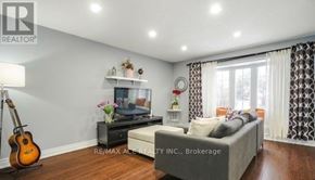 Toronto (Rouge) apartment for rent - A living room with a grey couch, a guitar, a TV, and a flower vase on a table.