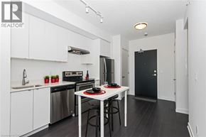 Burlington condo for rent - A modern kitchen with white cabinets and a black fridge.