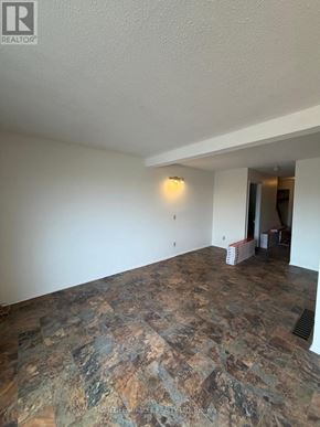 Kingston (West Of Sir John A. Blvd) townhouse for rent - A room with a stone floor and a white wall.