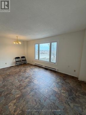 Kingston (West Of Sir John A. Blvd) townhouse for rent - A room with a large window and a tiled floor.