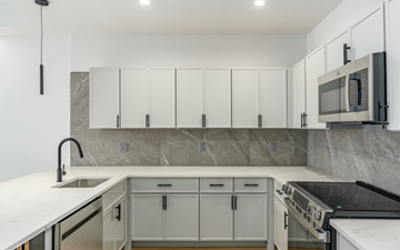 Portchester apartment for rent - A modern kitchen with white cabinets and a marble backsplash.