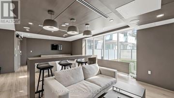 Toronto (Newtonbrook East) condo for rent - A modern living room with a grey sofa and a bar area.