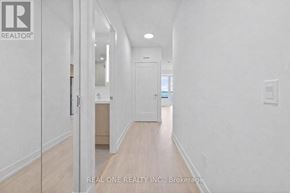 Toronto (Islington-City Centre West) condo for rent - A spacious room with a wooden floor and white walls, featuring a kitchen area with a refrigerator and cabinets.