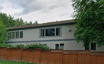 Anchorage apartment for rent - A grey house with a brown fence in front of it.