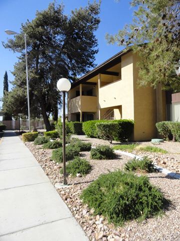 Boulder City apartment for rent - A white lamp post stands on a sidewalk in front of a tan building.
