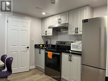 Toronto (Willowdale East) apartment for rent - A kitchen with white cabinets and a black stove top.