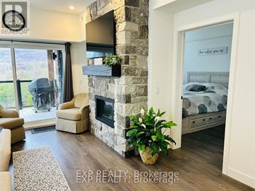 Blue Mountains condo for rent - A living room with a stone fireplace and a television mounted above it.