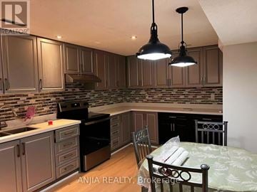 Mississauga (Erin Mills) apartment for rent - A kitchen with a table and chairs in the foreground and a backsplash of tiles.
