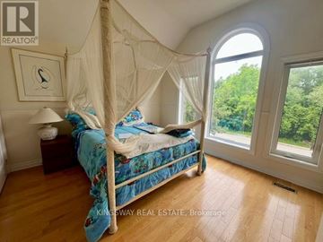 Mississauga (Rathwood) apartment for rent - A bedroom with a canopy bed and a view of trees outside the window.