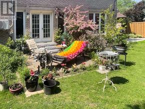 Mississauga (Rathwood) apartment for rent - A backyard with a patio, lawn, and a few potted plants.