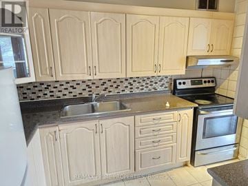 Toronto (Victoria Village) condo for rent - A kitchen with wooden cabinets and a black and white checkered backsplash.