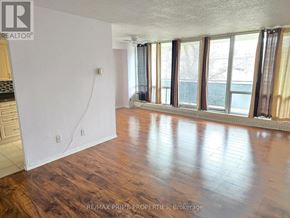 Toronto (Victoria Village) condo for rent - A room with wooden floors and a large window with curtains.