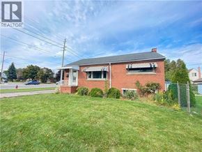 Hamilton apartment for rent - A red brick house with a white window and a fence in front of it.