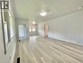 Hamilton apartment for rent - A spacious room with wooden flooring and white walls.