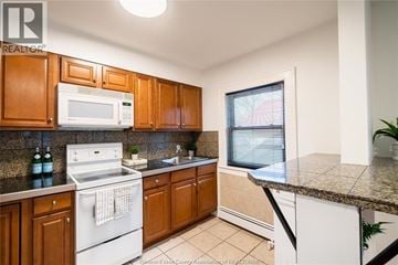 Windsor apartment for rent - A kitchen with wooden cabinets and a white stove top oven.