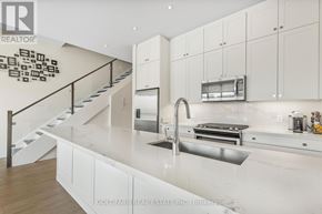 Innisfil townhouse for rent - A modern kitchen with white cabinets and a stainless steel sink.