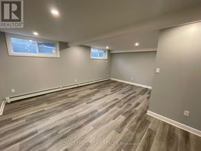 Ottawa multi-family for rent - A room with grey wooden flooring and two windows.