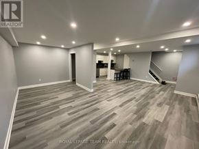 Ottawa multi-family for rent - A spacious room with wooden flooring and a bar area in the corner.