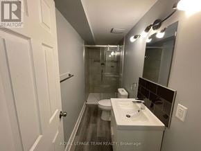 Ottawa multi-family for rent - A bathroom with a toilet, sink, and mirror.