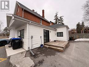 Barrie (City Centre) apartment for rent - A white house with a black trash bin and a wooden deck.