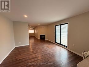 Barrie (City Centre) apartment for rent - A spacious room with wooden flooring and a fireplace.