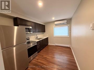 Barrie (City Centre) apartment for rent - A kitchen with stainless steel appliances and wooden floors.