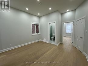 Toronto (Weston-Pellam Park) duplex for rent - A room with wooden flooring and white walls, with a doorway leading to another room.