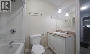 Hamilton condo for rent - A white toilet is in a bathroom with a sink and mirror.