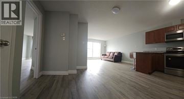 Hamilton condo for rent - A living room with a couch and a kitchen area in the background.