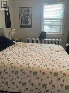 Guelph apartment for rent - A bed with a white comforter with a pattern of pineapples and leaves on it.