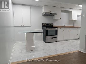 Barrie (Grove East) apartment for rent - A kitchen with a stove top oven and a table.