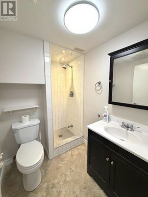 Newmarket (Central Newmarket) apartment for rent - A white toilet is in a bathroom with a black cabinet.