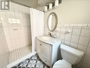 Niagara Falls (Morrison) apartment for rent - A white bathroom with a marble top vanity and a round mirror.