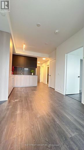 Toronto (Church-Yonge Corridor) condo for rent - A spacious room with wooden flooring and a white door on the right.