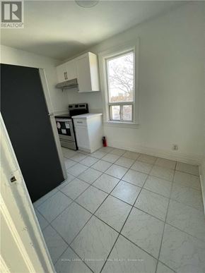 Toronto (Dovercourt-Wallace Emerson-Junction) triplex for rent - A kitchen with white cabinets and a black refrigerator.