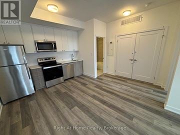 Kitchener townhouse for rent - A kitchen with a refrigerator, microwave, and stove top oven.