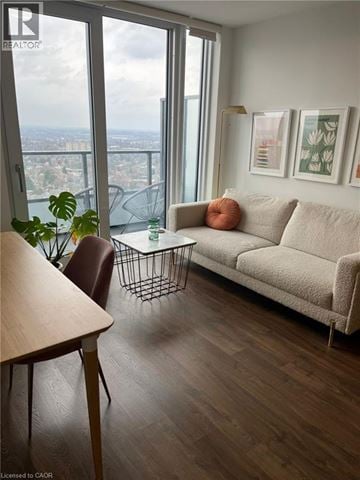 Kitchener condo for rent - A living room with a couch, chair, and a table with a plant on it.