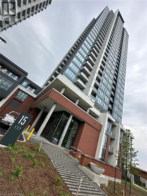 Kitchener condo for rent - A tall building with a glass facade stands next to a smaller building with a brick facade.