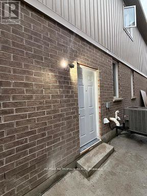 Oshawa (Eastdale) apartment for rent - A white door is on the right side of a brick building.