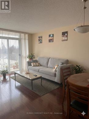Toronto (Scarborough Village) condo for rent - A living room with a grey couch, a coffee table, and a lamp.