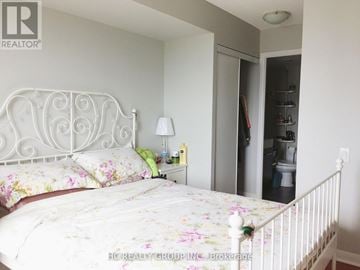 Toronto (Bendale) condo for rent - A bedroom with a floral bedspread and a white metal bed frame.