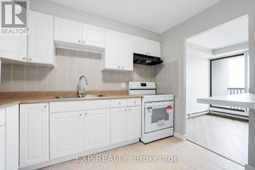 Ottawa condo for rent - A kitchen with white cabinets and a stove top oven.