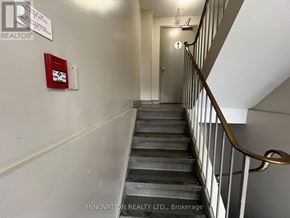 Ottawa condo for rent - A staircase with a red box on the wall and a sign that says "INNOVATION REALTY LTD., Brokerage".