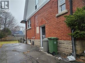 Hamilton apartment for rent - A red brick house with a green trash bin outside.