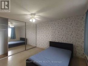 Ottawa condo for rent - A bedroom with a bed, a ceiling fan, and a wallpapered wall.