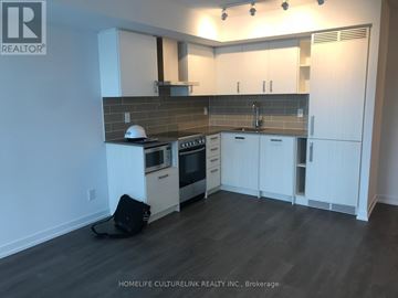 Toronto (Mount Pleasant West) condo for rent - A kitchen with white cabinets and a black bag on the floor.