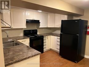 Aurora (Aurora Heights) apartment for rent - A black refrigerator stands in a kitchen with white cabinets.