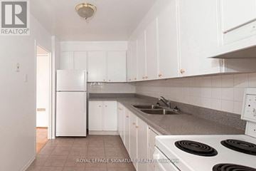 Toronto (Mount Pleasant East) house for rent - A white kitchen with a refrigerator and stove.